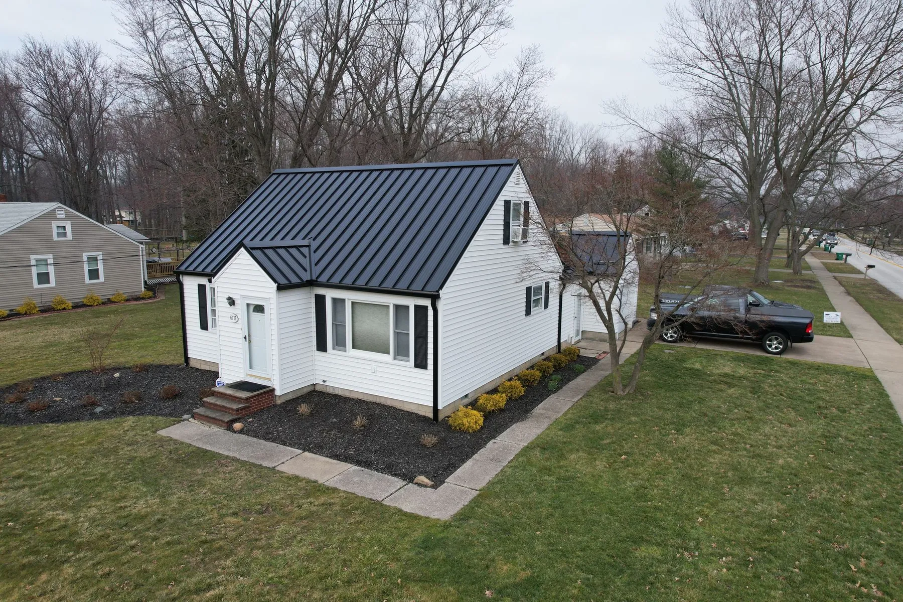 Finished residential metal roof installation on a white home, reflecting professional project management, quality workmanship, and exceptional customer satisfaction.