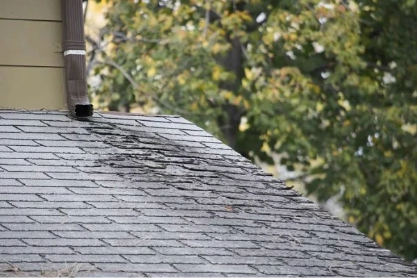 Cracked and deteriorating asphalt shingles on a residential roof showing signs of age-related wear