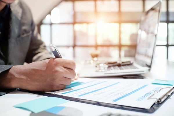 A person reviewing and signing documents on a clipboard, representing the roof inspection records and documentation that support insurance claims and warranty coverage.